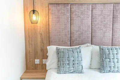 a bedroom with a bed with white pillows and a lamp at Tastefully decorated lodge on popular holiday park, easy access to Lakes and Dales and free parking in Carnforth