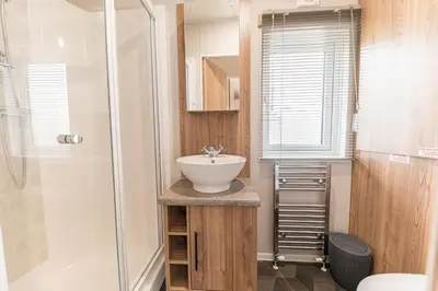 a bathroom with a sink and a shower at Tastefully decorated lodge on popular holiday park, easy access to Lakes and Dales and free parking in Carnforth