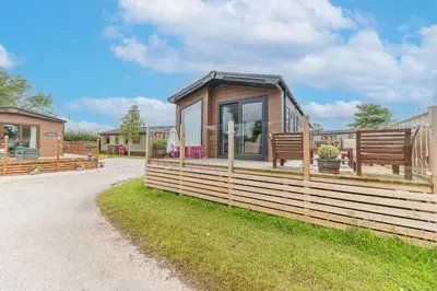 a tiny house with a fence and two benches at Tastefully decorated lodge on popular holiday park, easy access to Lakes and Dales and free parking in Carnforth