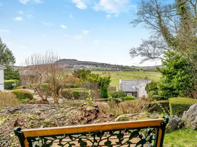 a wooden bench sitting in the middle of a garden at The Cottage At Breeze Hill in Storth