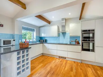 a kitchen with white cabinets and a wooden floor at The Cottage At Breeze Hill in Storth