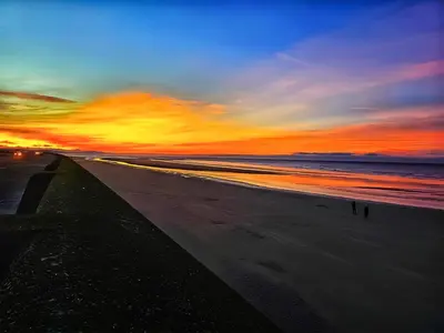 a sunset on a beach with the ocean at The Hideaway in Great Meols