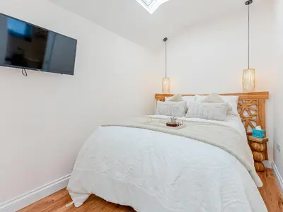 a bedroom with a bed with a tv on the wall at The Hideaway in Great Meols