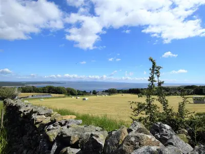 a stone wall with a field and the ocean in the background at 2 Bed in Grange-over-sands oc-73544 in Grange Over Sands