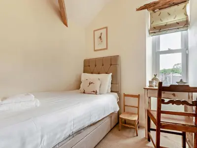 a bedroom with a bed and a chair and a window at 2 Bed in Grange-over-sands oc-73544 in Grange Over Sands