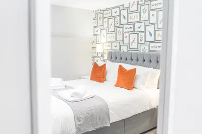 a bedroom with a bed with orange pillows at Chequers Lodge- Dalton-in- Furness- Self check in- for professionals and tourists in Dalton in Furness