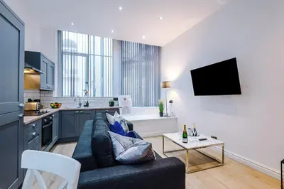a living room with a couch and a kitchen at Modern 2-Bedroom Apt In the Heart of City Centre in Liverpool