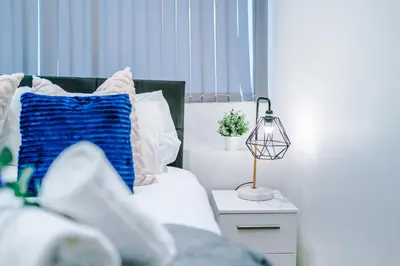 a bed with a blue pillow and a lamp on a table at Modern 2-Bedroom Apt In the Heart of City Centre in Liverpool