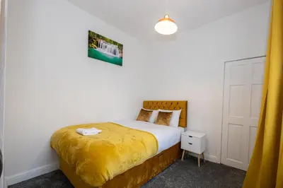 a bedroom with a bed with a yellow blanket at Cosy Four Bedroom Terrace Rishton in Rishton