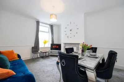 a living room with a blue couch and a table at Cosy Four Bedroom Terrace Rishton in Rishton