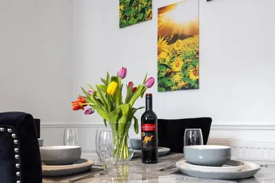a table with a bottle of wine and a vase of flowers at Cosy Four Bedroom Terrace Rishton in Rishton