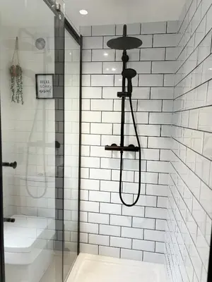 a shower in a white tiled bathroom at Hardy Hideaway in Ulverston