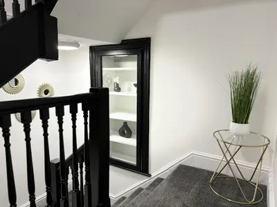 a hallway with a mirror and a staircase with a plant at Hardy Hideaway in Ulverston