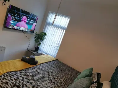a bedroom with a bed and a flat screen tv at Unique LFC Themed House in Liverpool