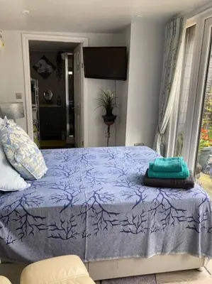 a bedroom with a bed with a purple comforter at Beautiful new Garden Annexe in Ashton in Makerfield