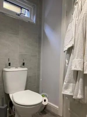 a bathroom with a toilet and a window and towels at Beautiful new Garden Annexe in Ashton in Makerfield