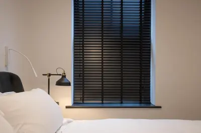 a bedroom with a window with black blinds at Lord Street Lofts in Southport