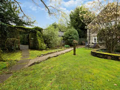a garden with a stone wall and a house at 1 Bed in Cartmel LCC15 in Cartmel