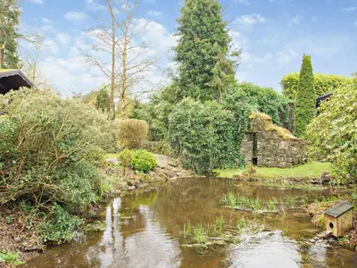 a pond in a garden with a bird house in it at 1 Bed in Cartmel LCC15 in Cartmel