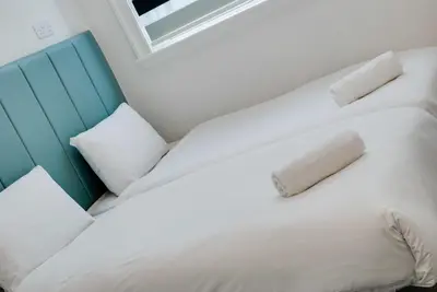 a white bed with a blue headboard and white pillows at Temple Court Cavern Quarter Apartments by Happy Days in Liverpool