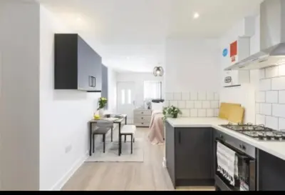 a white kitchen with a table and a dining room at The Residency rooms Liverpool in Wallasey