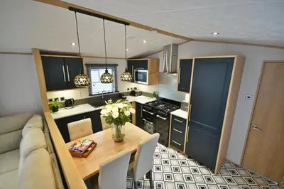 a kitchen with a table and a couch and a kitchen with a table and chairs at Pendle View Retreat - Holiday Park in Clitheroe