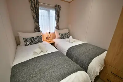 two twin beds in a room with a window at Pendle View Retreat - Holiday Park in Clitheroe