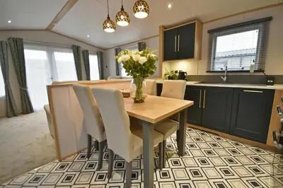 a kitchen with a table with chairs and a vase of flowers at Pendle View Retreat - Holiday Park in Clitheroe