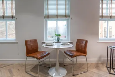 a table and two chairs in a room with windows at Winckley Chambers in Preston