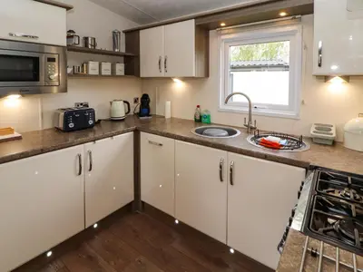a kitchen with white cabinets and a sink and a window at Lakeside Haven in Carnforth