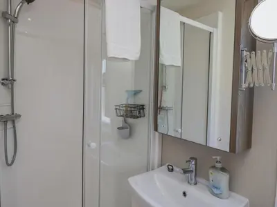 a bathroom with a sink and a shower with a mirror at Lakeside Haven in Carnforth