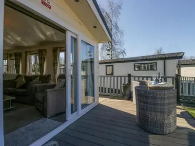 a patio with a couch and a table on a deck at Lakeside Haven in Carnforth