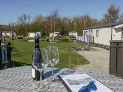 a table with two glasses and a bottle of wine at Lakeside Haven in Carnforth