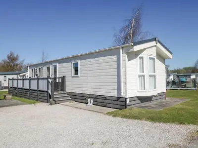 a white house with a cat sitting in front of it at Lakeside Haven in Carnforth