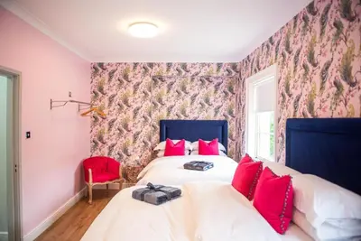 a bedroom with two beds and a red chair at Liverpool Georgian Quarter Townhouse Rodney St in Liverpool