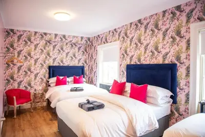two beds in a bedroom with a floral wallpaper at Liverpool Georgian Quarter Townhouse Rodney St in Liverpool