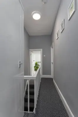a hallway with a staircase with a mirror and white walls at Newcombe House - Air Host & Stay - Free Parking - Contractor Friendly in Liverpool