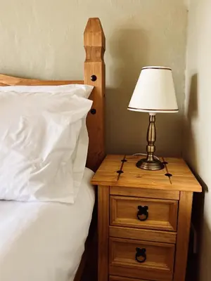 a bed with a nightstand with a lamp on it at Holly Cottage in Cartmel