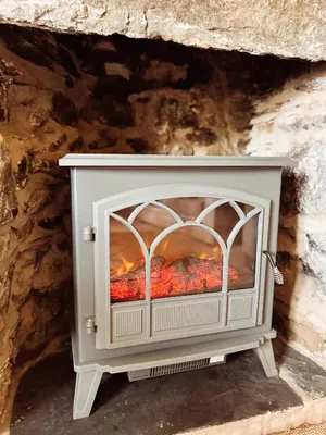 a fireplace in a stone wall at Holly Cottage in Cartmel