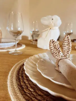 a table with a white plate and wine glasses at Holly Cottage in Cartmel