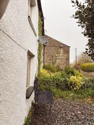 a bench sitting outside of a building with a sign at Holly Cottage in Cartmel