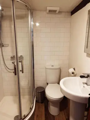a bathroom with a toilet and a sink and a shower at Holly Cottage in Cartmel