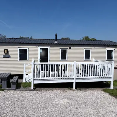 a white house with a porch and a white fence at McCanns Caravan Marton Mere in Blackpool