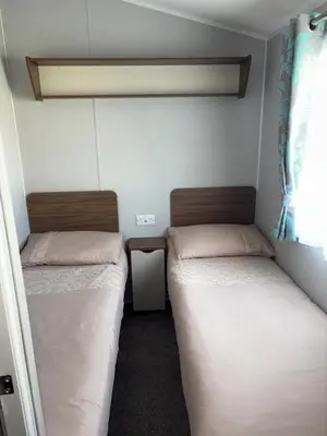 a small room with two beds and a window at McCanns Caravan Marton Mere in Blackpool