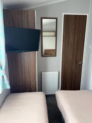 a small room with two beds and a mirror at McCanns Caravan Marton Mere in Blackpool