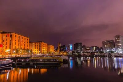a city skyline at night with boats in the water at Maldron Hotel Liverpool City Centre in Liverpool
