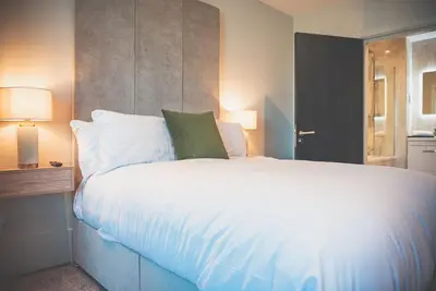a bedroom with a large bed with white sheets and green pillows at 2BR Apt - Balcony - River View in Liverpool