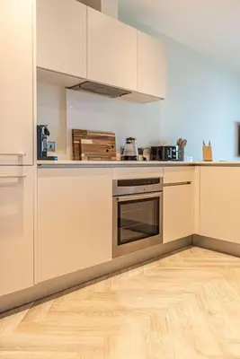 a kitchen with white cabinets and a wooden floor at 2BR Apt - Balcony - River View in Liverpool