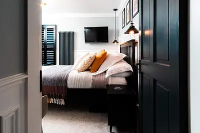 a bedroom with a bed with a tv on the wall at East Cliff in Preston