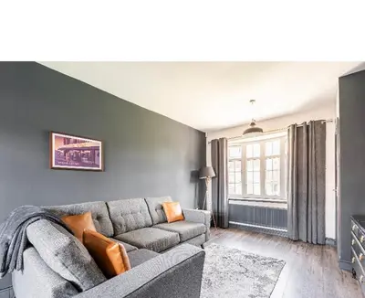 a living room with a gray couch and a window at T'house in wigan in Pemberton